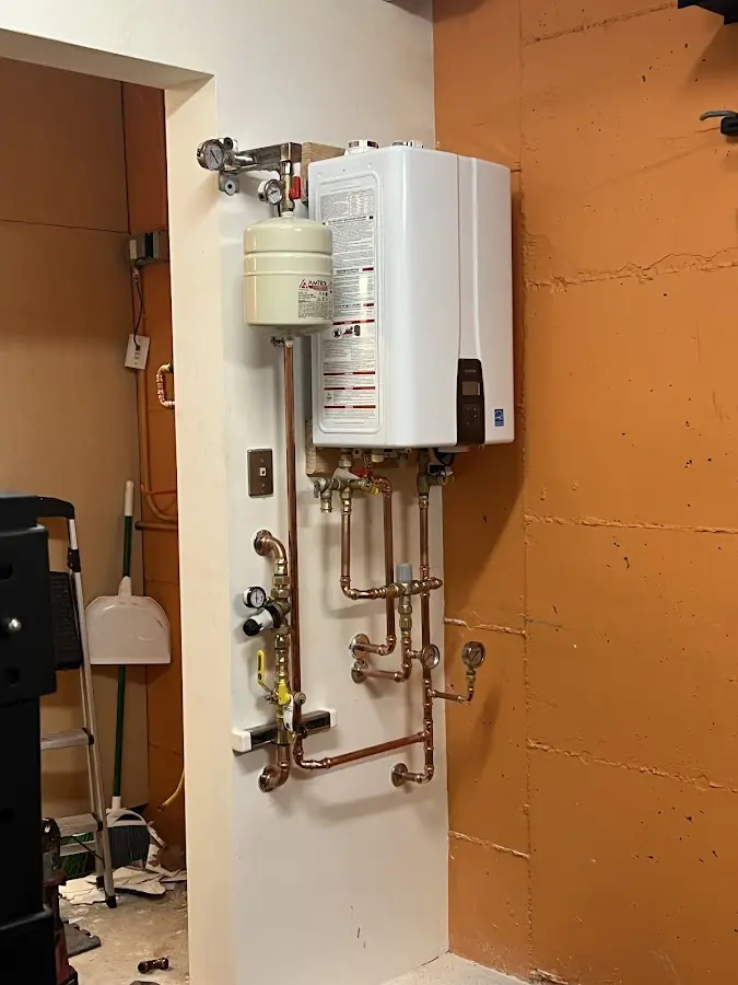 Plumbing technician inspecting water heater connections in Gilford